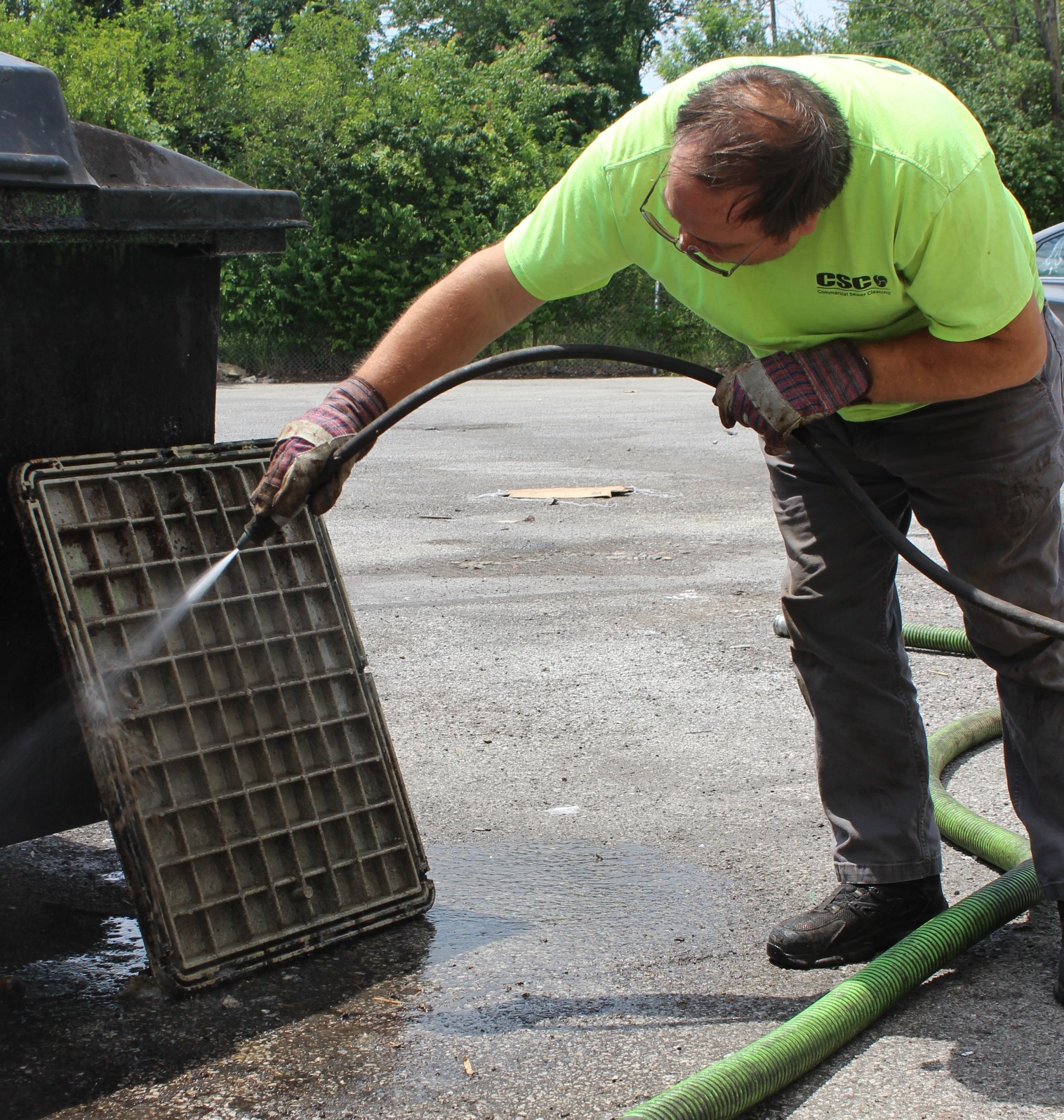 Technician connecting a suction hose to a grease trap for cleaning